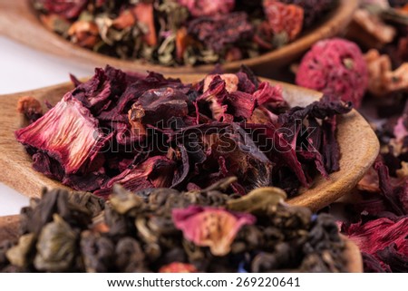 Dry tea in wooden spoons on white background. Leaves of red, green and black tea. Macro photo.