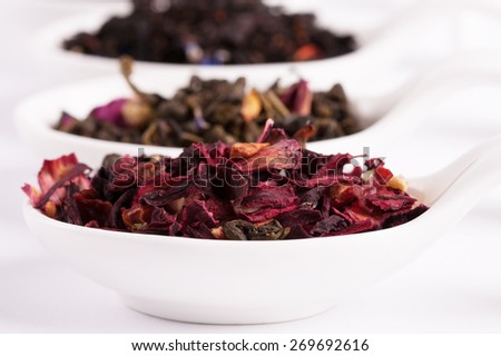 Dry tea in white bowls, on white background. Leaves of red, green and black tea. Macro photo.
