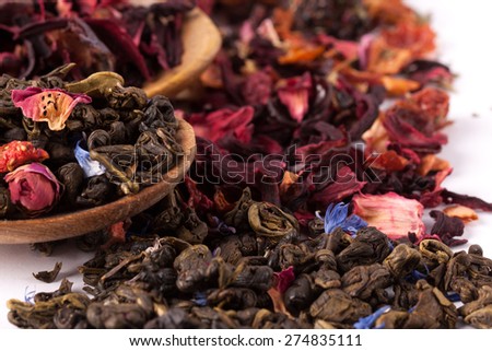 Dry tea in wooden plates and spoons, on white background. Leaves of red, green and black tea. Macro photo.