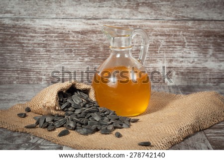 Sunflower oil and sunflower seeds in small sack on traditional rustic wooden background