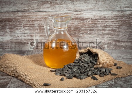 Sunflower oil and sunflower seeds in small sack on traditional rustic wooden background