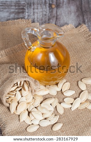 Pumpkin seed oil in a glass bottle on a brown rustic traditional wooden table