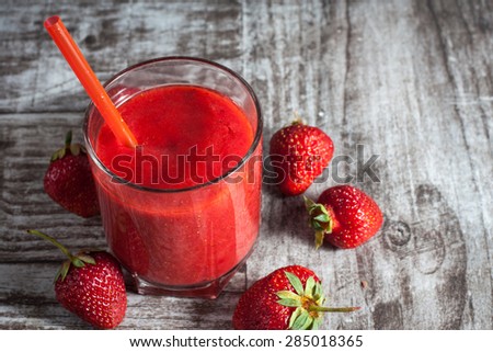A glass of fresh strawberry smoothie on a wooden background. Summer drink and refreshment organic concept.