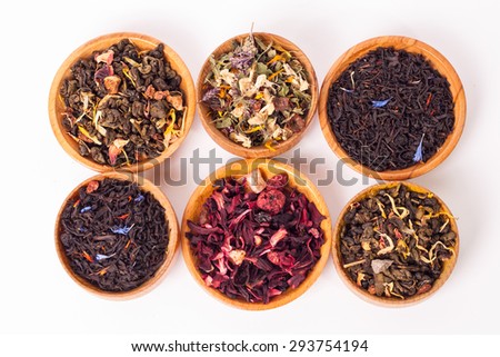 Dry tea in wooden plates and spoons, on white background. Leaves of red, green and black tea. Macro photo. Rustic style and concept.