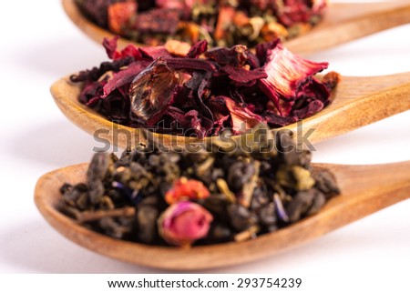 Dry tea in wooden plates and spoons, on white background. Leaves of red, green and black tea. Macro photo. Rustic style and concept.