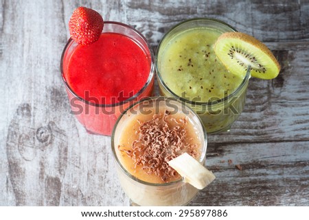 Fresh Made Chocolate Banana Smoothie, kiwi juice and strawberry juice on a wooden table. Selective focus. Milkshake. Protein diet. Healthy food concept.