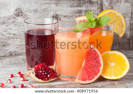 Glasses of pomegranate, grapefruit, orange juice on wooden background. Refreshments and summer drinks.