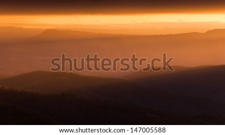 The sun shining through the mist on the Shenandoah Valley and Appalachian Mountains, seen from Skyline Drive in Shenandoah National Park at sunset.