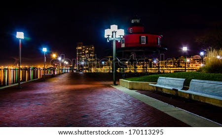 Waterfront promenade and lighthouse at night in the Inner Harbor, Baltimore, Maryland.