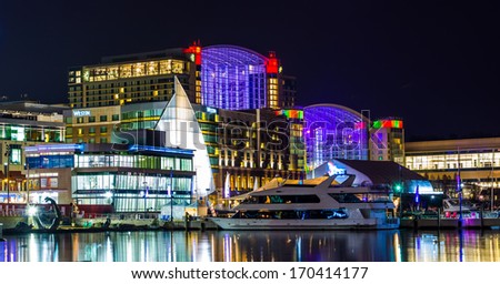 Buildings and a boat on the shore of the Potomac River at night, in National Harbor, Maryland.