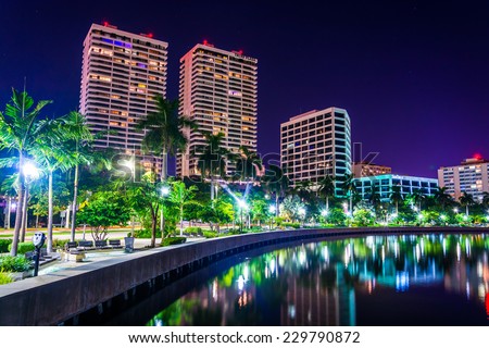 Palm trees along the Intracoastal Waterway and the skyline at night in West Palm Beach, Florida.
