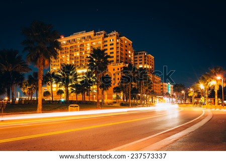 Traffic moving past a hotel and palm trees on Coronado Drive at night, in Clearwater Beach, Florida.