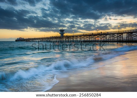 Waves in the Pacific Ocean and the pier at sunset, in Seal Beach, California.