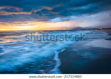Dramatic stormy sunset and waves in the Pacific Ocean, seen at Venice Beach, Los Angeles, California.