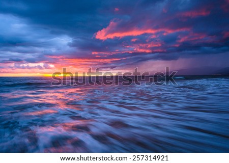 Dramatic stormy sunset and waves in the Pacific Ocean, seen at Venice Beach, Los Angeles, California.