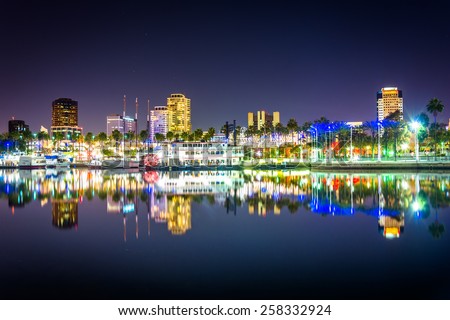 Buildings and boats reflecting in the harbor at night, seen from Shoreline Aquatic Park in Long Beach, California.