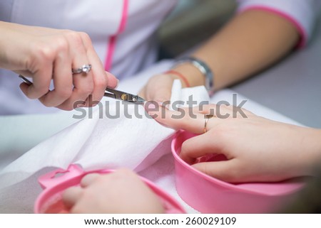 Finger nail care by manicure specialist in beauty salon