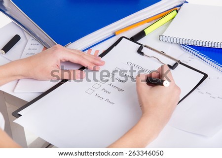 Human hands with pen filling customer survey blank
