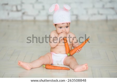 Portrait of a cute baby dressed in Easter bunny ears with a carrot