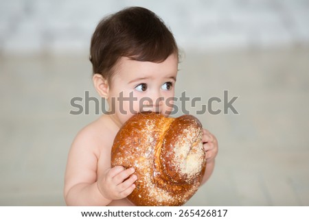 Portrait of cute baby with  bread in her hands eating