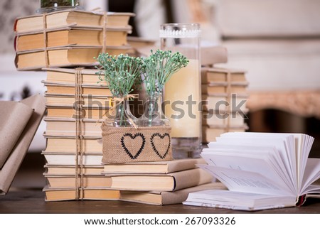 Interior rustic decoration with books heap, candles and flowers in glass bottles