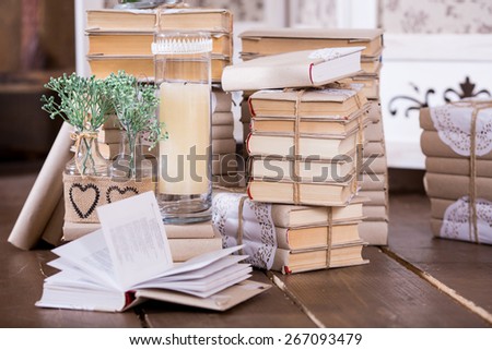 Interior rustic decoration with books heap, candles and flowers in glass bottles