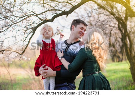 Family walk in the spring garden; mother, father and little daughter
