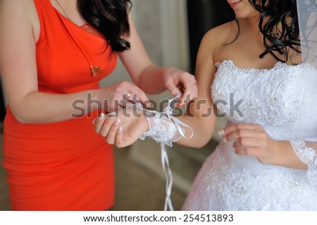 Bridesmaids helps tie gloves
