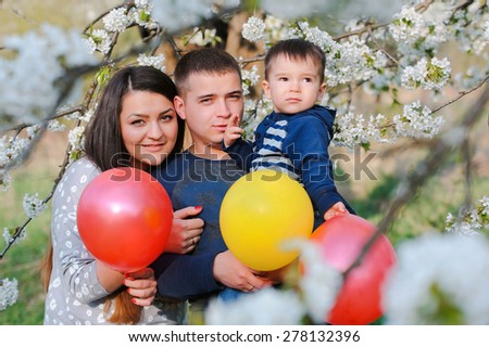 Portrait of family outdoors in blooming spring garden with colorful balloons