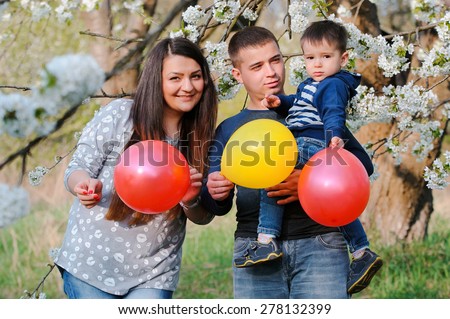 Portrait of family outdoors in blooming spring garden with colorful balloons