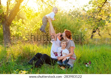 Father, mother and two sons are playing in the garden on sunset