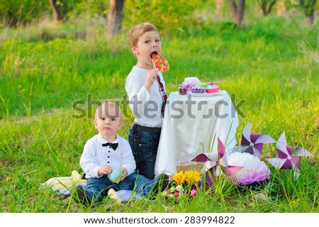 Cute little brothers sat at the table with cupcakes and candy