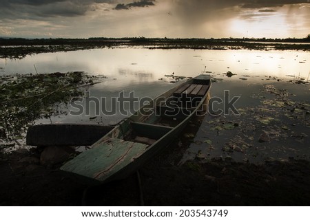 Storm clouds over water landscape old wooden fishing canoe