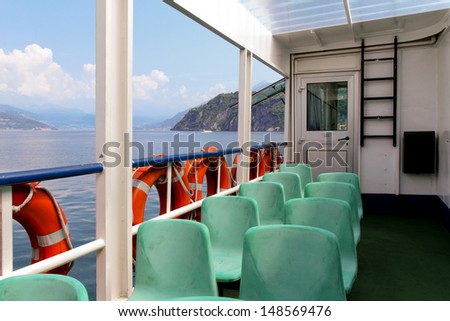 The empty ferry boat. with green seats and red lifebuoy. In the background Como lake, Italy