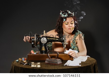 adult woman in curlers sitting at table sewing dress