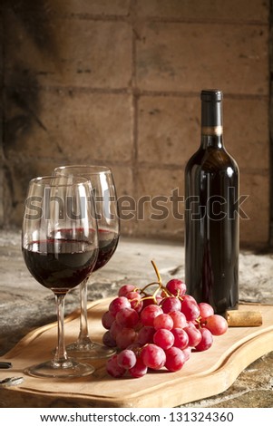 Two wine cups, grapes and a bottle of red wine