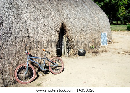 Traditional Amazon Indian house with doorway and modern technology: bicycle, black pot and solar panel