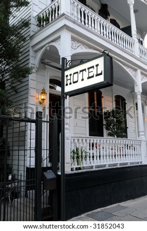 Romantic Victorian style hotel with a lit sign and porch
