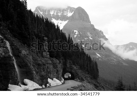 A black and white photo of a tunnel on the Going-to-the-Sun Road of a foggy valley in the Logan Pass in the Glacier National Park in Montana, northwestern USA, shot in early July.