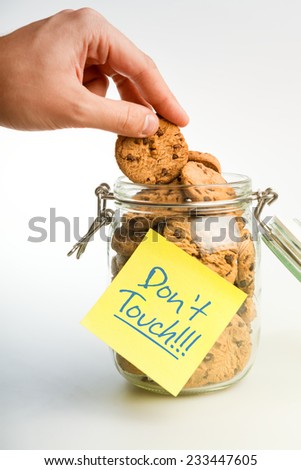 A Hand Taking Cookies from a Glass Cookie Jar