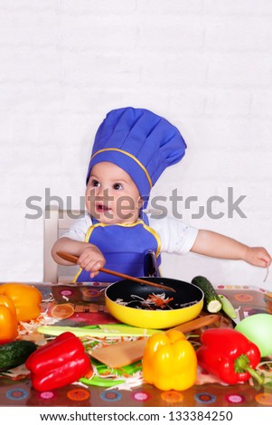 adorable baby cooking in kitchen. little cute child in costume of Cook.  funny child makes a dinner