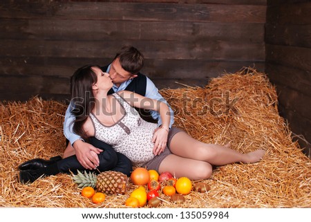 Portrait of a happy young pregnant woman with her husband. young pregnant couple. The beautiful couple pregnant wife and the husband enjoyed stay on hay