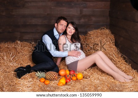 Portrait of a happy young pregnant woman with her husband. young pregnant couple. The beautiful couple pregnant wife and the husband enjoyed stay on hay