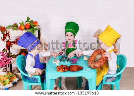 children in a chef\'s hats eating bread. beautiful children prepare in kitchen