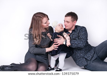 Happy family with  child - beautiful mother and father hug their daughter, posing on white background in studio closeup