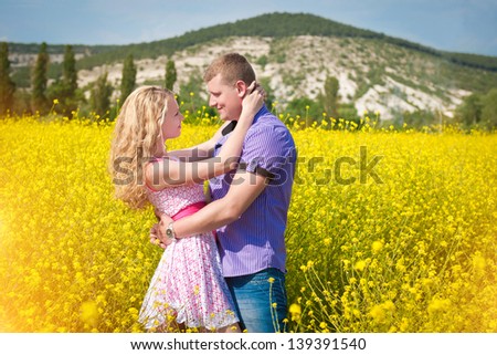 couple in love enjoy a moment of happiness  in blossom spring garden with field flowers on nature. handsome young man and beautiful blond girl  happy. Loving couple on date in park looking happy