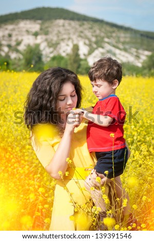 Happy family with child -beautiful mother hug with her son,resting in blossom spring garden with field flowers on nature looking happy smiling outdoors.Smiling  girl with healthy hair on nature