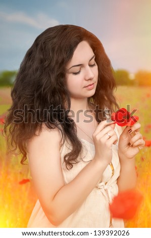 Happy beautiful woman resting in blossom spring garden with field flowers on nature looking happy smiling outdoors. Brunette girl on grass in park enjoying  life. Indian woman in country summer dress