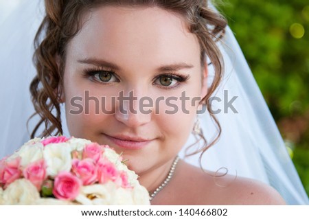 happy beautiful bride holding beautiful wedding bouquet of purple, pink, yellow and white flowers. Slim newlywed woman with fresh flowers at her wedding day waiting for groom outdoors