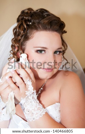 Gorgeous bride brunette with wedding bouquet makeup and hairstyle in bridal dress diamond jewelry at home waiting for groom. Jewelry and beauty. Rich happy girl have final preparation for wedding